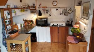Links: Beistelltisch mit Rollen, Anrichte (Marmorplatte). Mitte: Platte mit Mini-Backofen, 3-flammigen Gasherd, Wasserkocher. Rechts: Spüle, Küchenbüffet, rechts daneben (nicht sichtbar): Tür zumr Abstellkammer